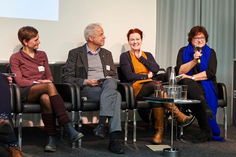 Foto: Politik- & Hochschulvertretende auf dem Podium: Petra Wontorra hält ein Mikro; sie schmunzelt bei einer Publikumsfrage. Auch Katja Dörner, Jörg Wolstein und Britt Dahmen lächeln.