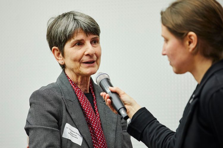 Foto: Doktorin Christiane Schindler der bundesweiten Informations- & Beratungsstelle (IBS) "Studium und Behinderung" stellt von ihrem Publikumsplatz eine Frage über Mikrofon an die Podiumsgäste.